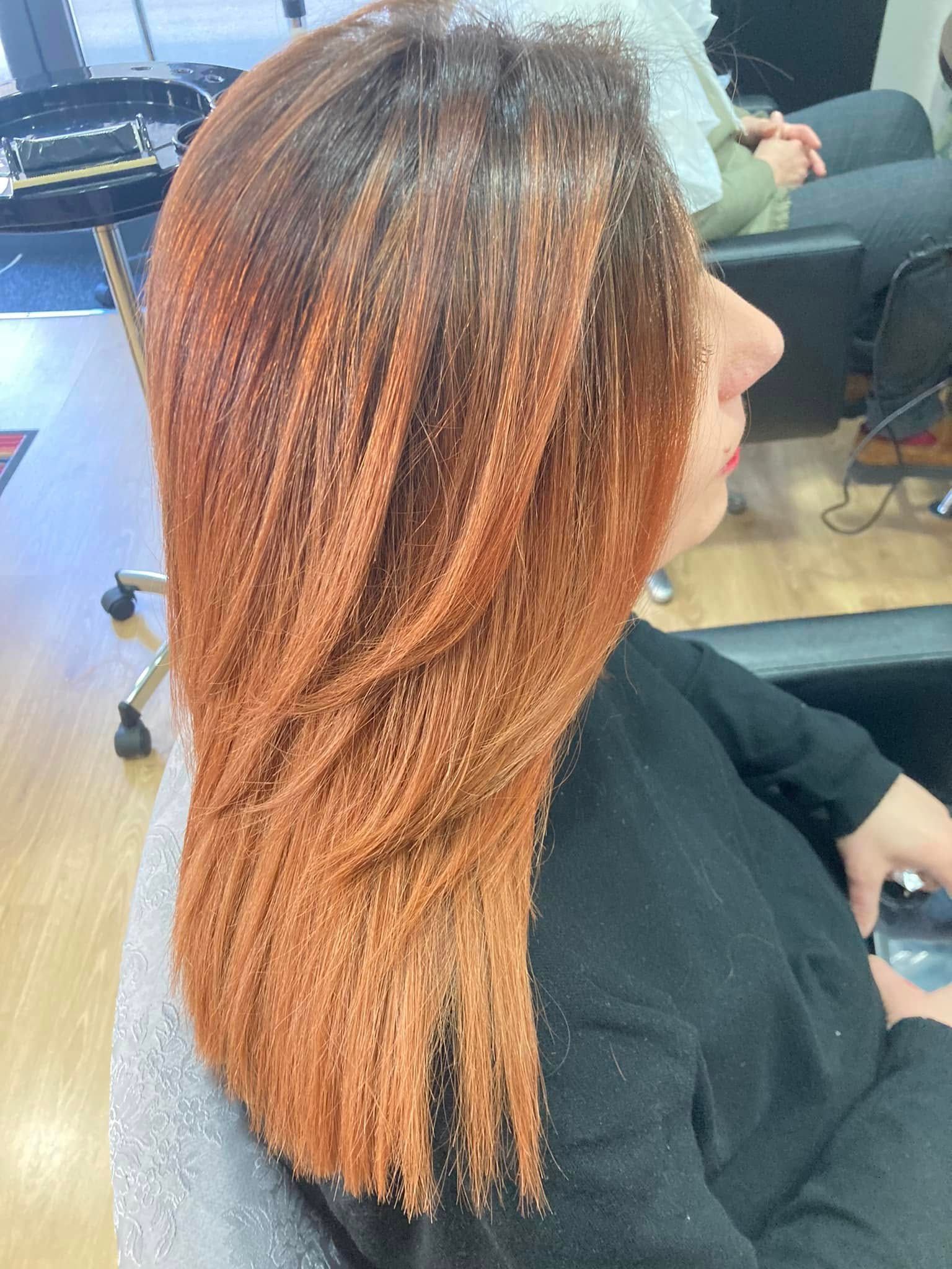 Una donna con lunghi capelli rosso-arancio è seduta su una poltrona del salone.