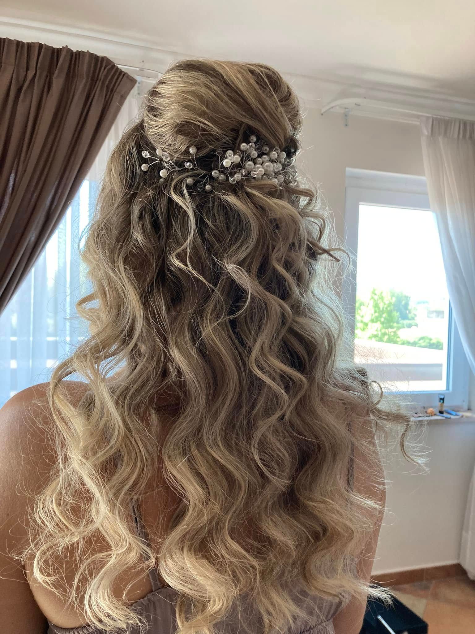 Donna con capelli biondi e ondulati, raccolti a metà con un fermaglio floreale.