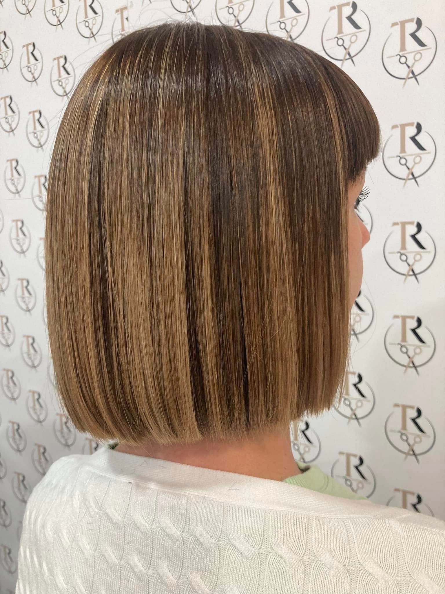 Donna con un caschetto lungo fino al mento, acconciato liscio con mèches, che indossa un maglione chiaro.