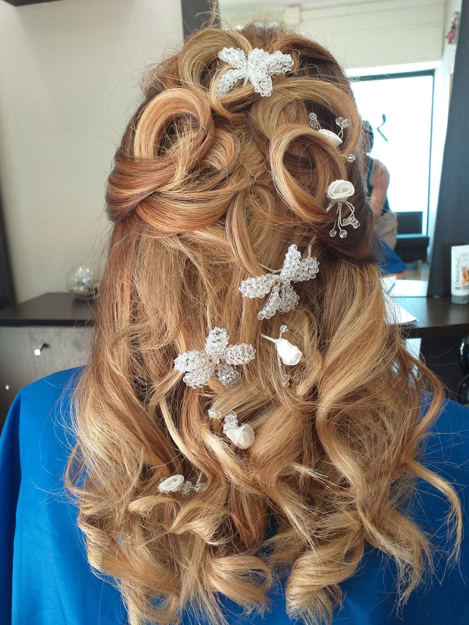 Donna con acconciatura raccolta con riccioli e accessori per capelli con fiori bianchi.