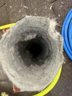 Hole in insulated pipe, dark interior, gray and white insulation, yellow and blue hoses alongside.