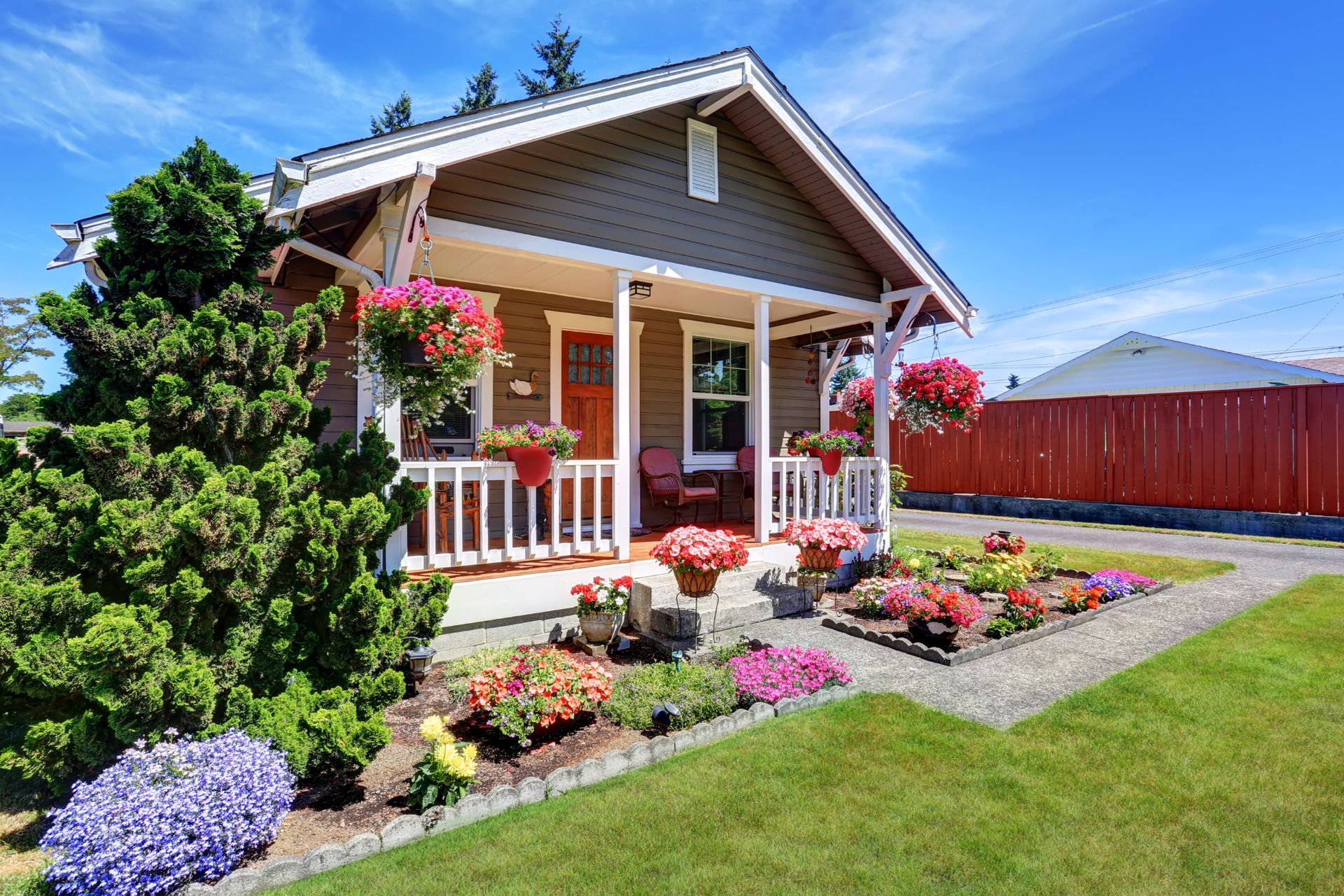 A house with a porch and flowers in front of it.