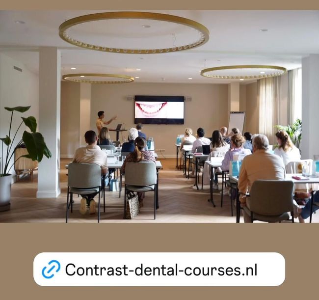 Een tandheelkundige cursus is gaande. De deelnemers zitten aan bureaus en kijken naar een presentatie op een scherm.