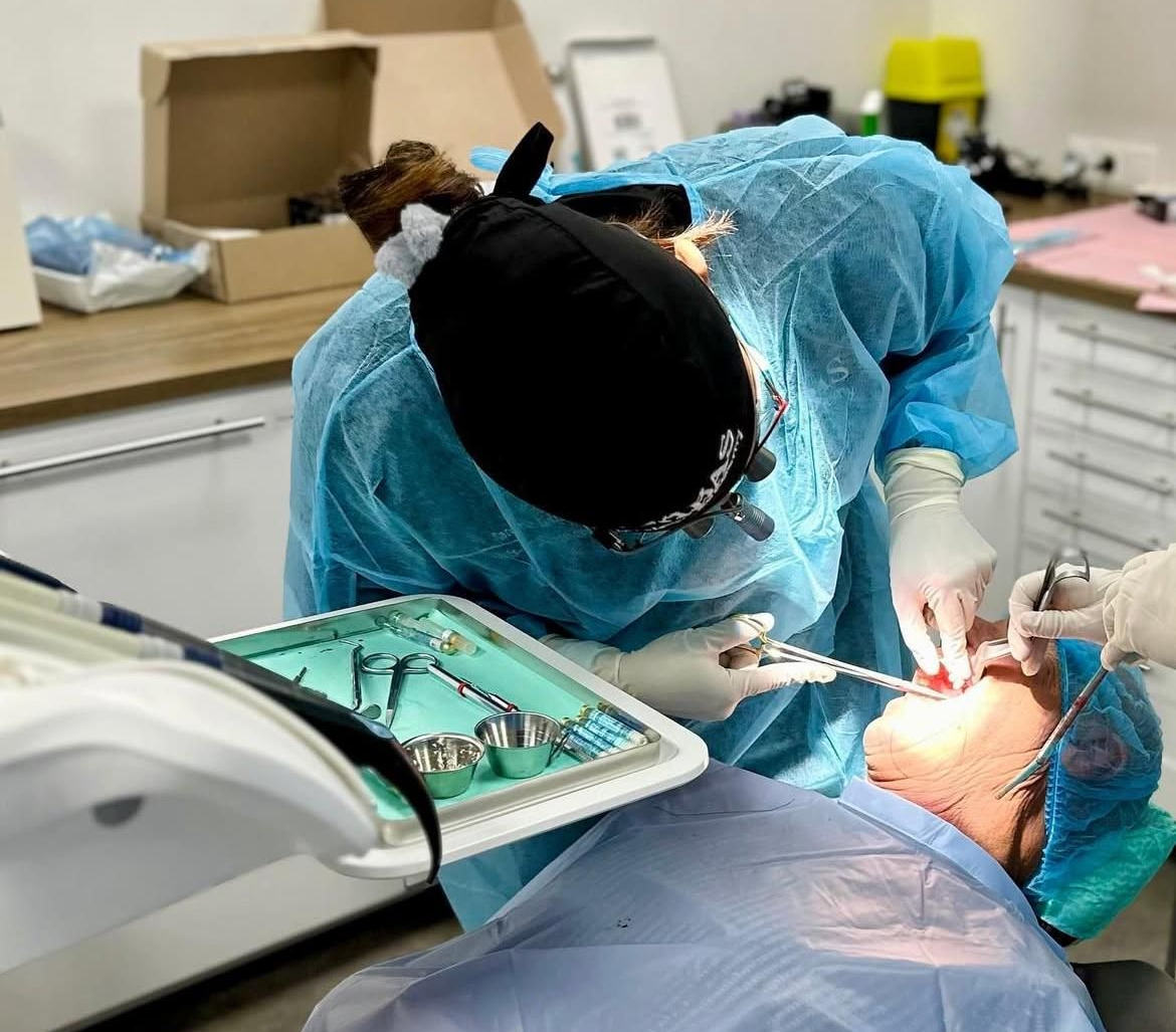 Tandarts die een tandheelkundige ingreep uitvoert bij een patiënt in een onderzoekskamer.