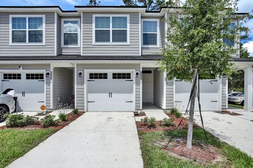 Townhouses with gray siding, white garage doors, and a concrete driveway.
