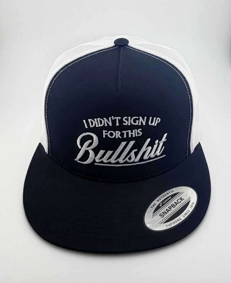 A navy blue and white trucker-style snapback hat with the embroidered white text 