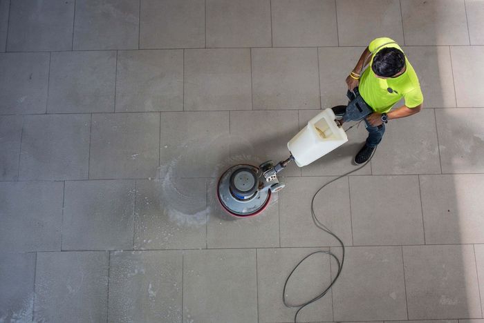 A man is cleaning a tiled floor with a machine.