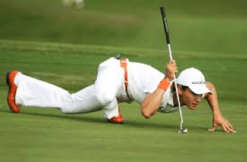 A man is crawling on the grass while holding a golf club.