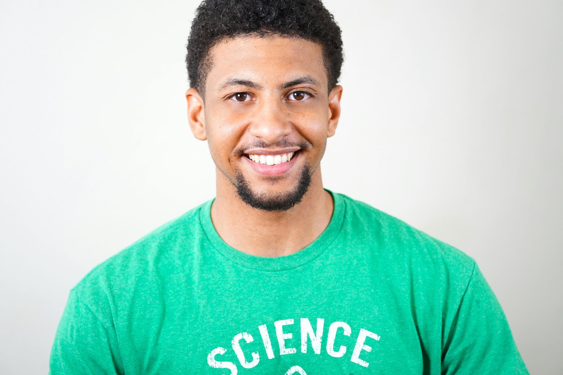 A man wearing a green science t-shirt is smiling for the camera.