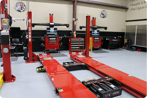 An auto repair shop with red lifts and alignment equipment. | Auto Check Elite