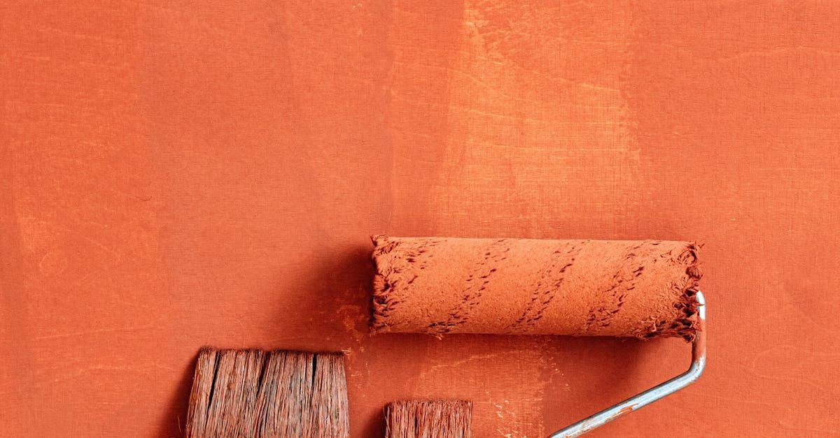 A paint roller is being used to paint a red wall.