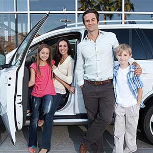 Happy family next to white car—insurance policy in County, MN