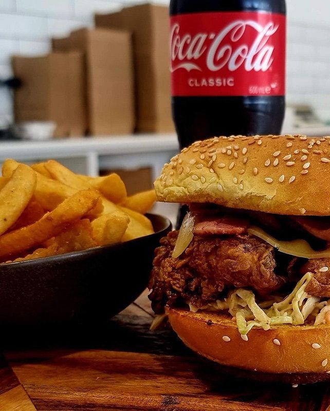 A Chicken Sandwich Next to a Bowl of French Fries and a Bottle of Coca Cola — Carpenter Carvery in Wendouree, VIC