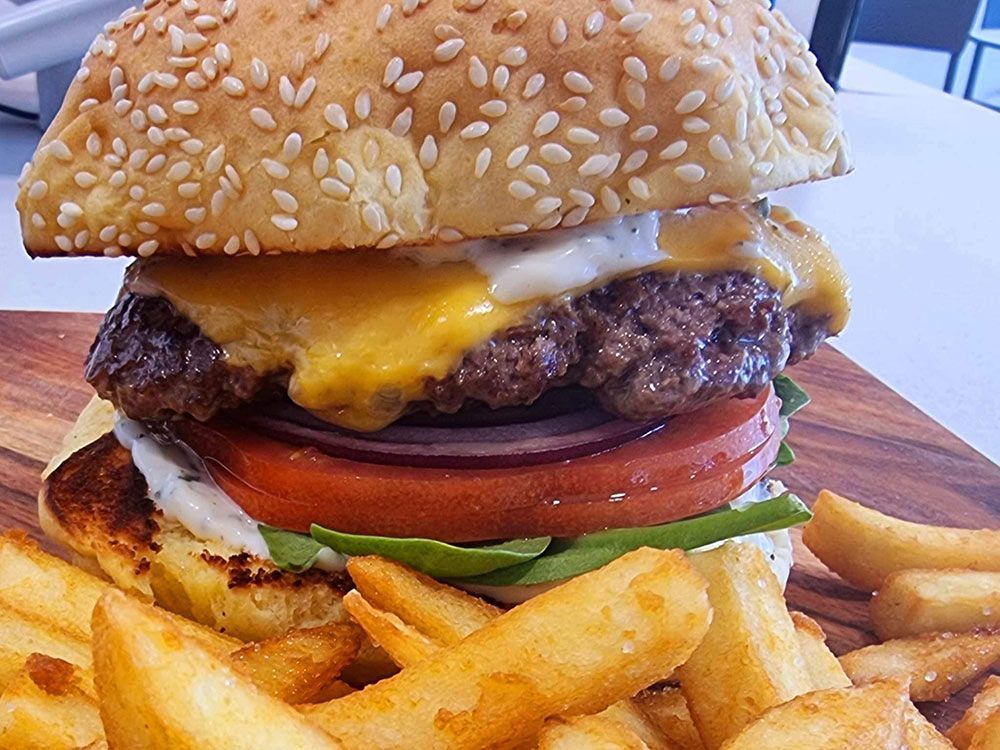 A Hamburger With French Fries on a Wooden Cutting Board — Carpenter Carvery in Wendouree, VIC