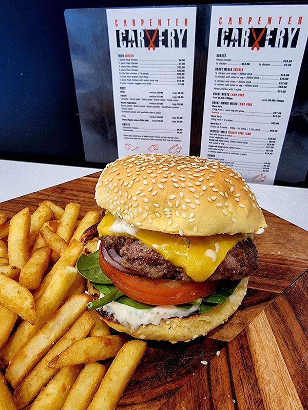A Hamburger and French Fries Are on a Wooden Cutting Board — Carpenter Carvery in Wendouree, VIC