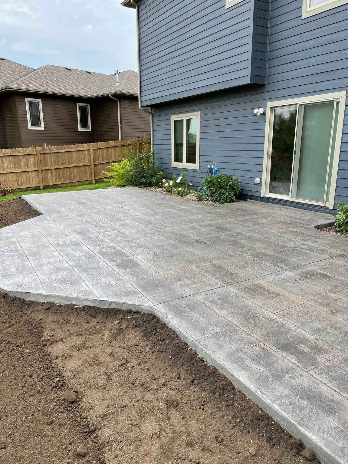 A concrete patio is being built in front of a blue house.