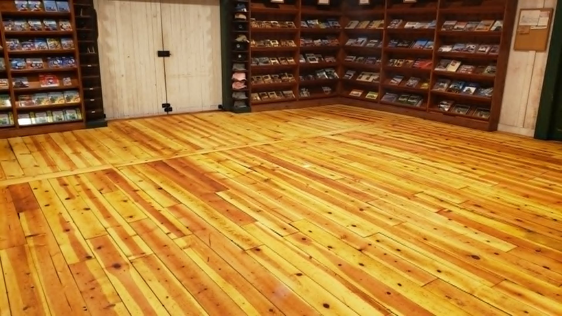 Empty room with polished wooden floor and walls of shelves filled with packaged items