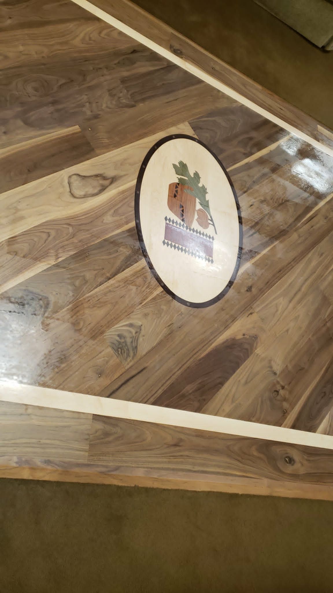 Oval wall plaque with a small colorful illustration on a wooden surface, framed by light trim.