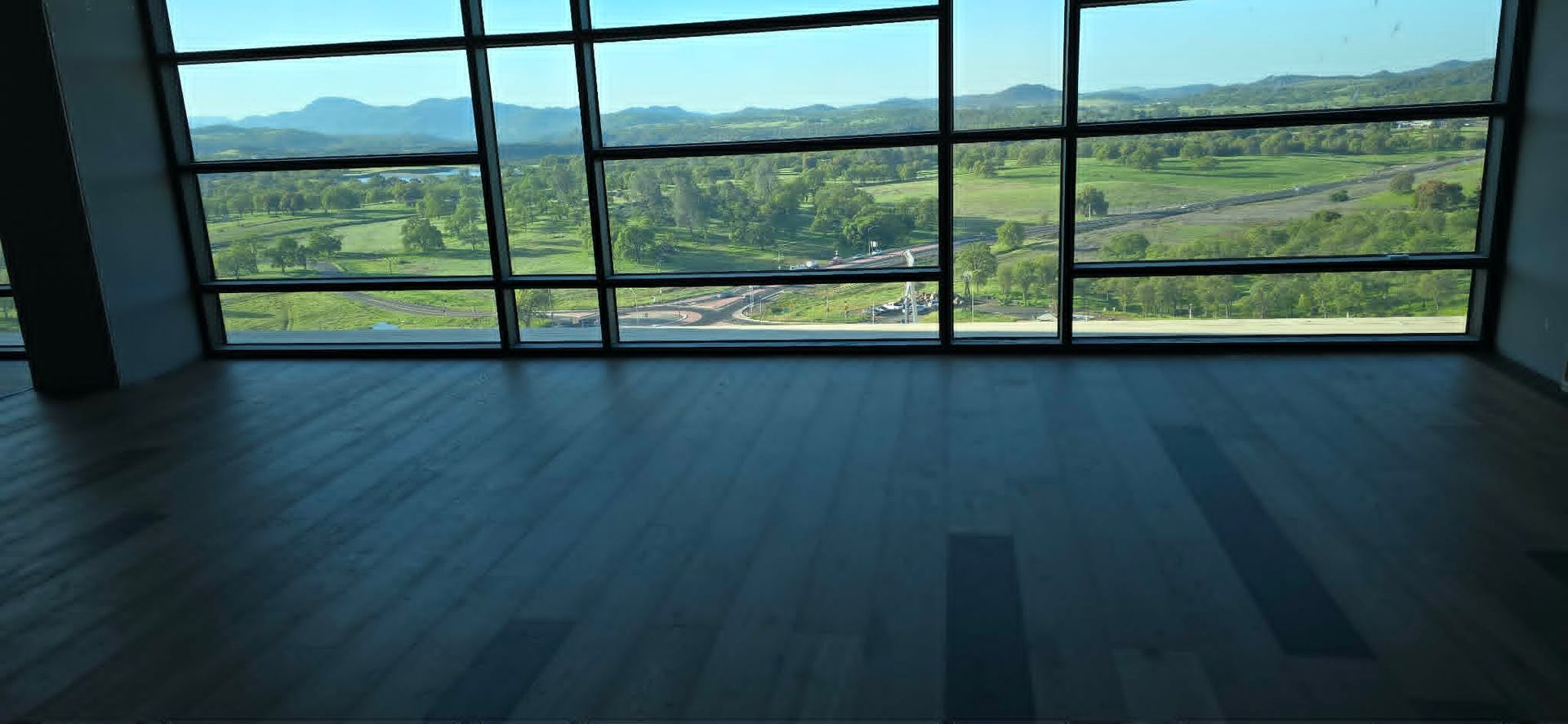 Empty room with wide windows overlooking a green valley and mountains
