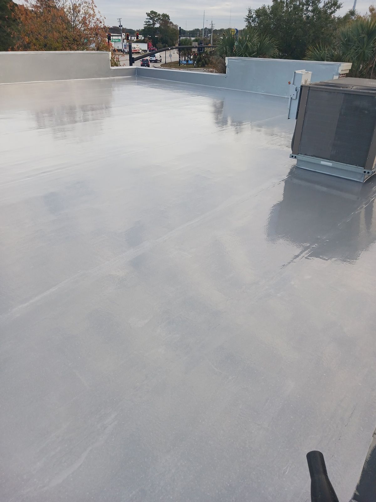 Gray, reflective rooftop. An air conditioning unit and cityscape are visible in the background.