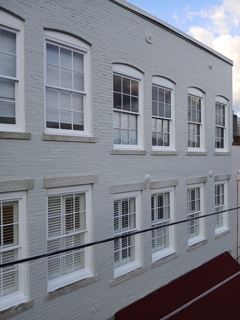 Gray brick building with multiple white-framed windows; power lines in foreground.