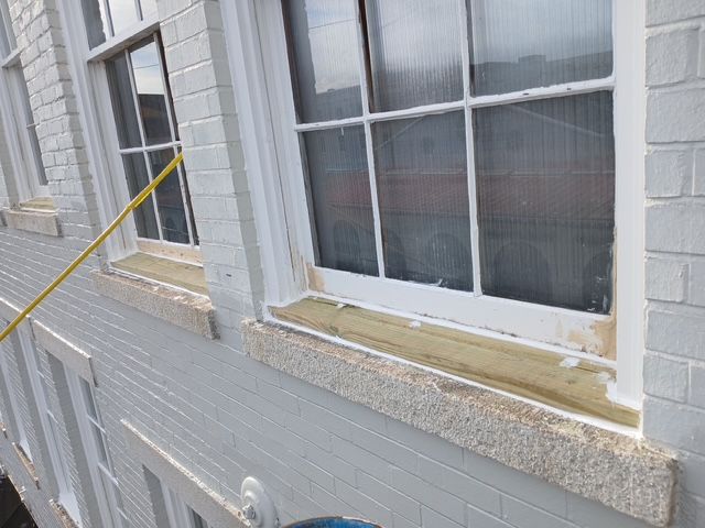 Exterior of a building with white windows and brick. A yellow pole is in the frame.
