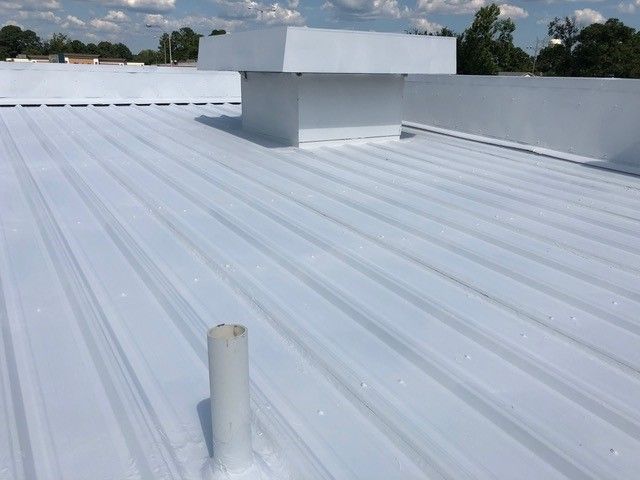 White metal commercial roof with a vent and a pipe.