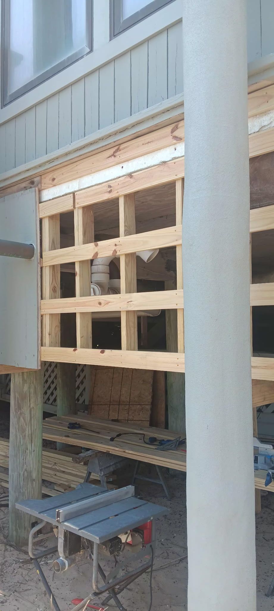 Wooden frame under construction, possibly for an outdoor structure; building foundation and column visible.