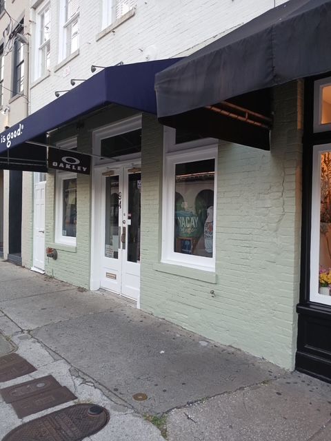 Oakley store exterior with blue awning, white doors and windows, on a city street.