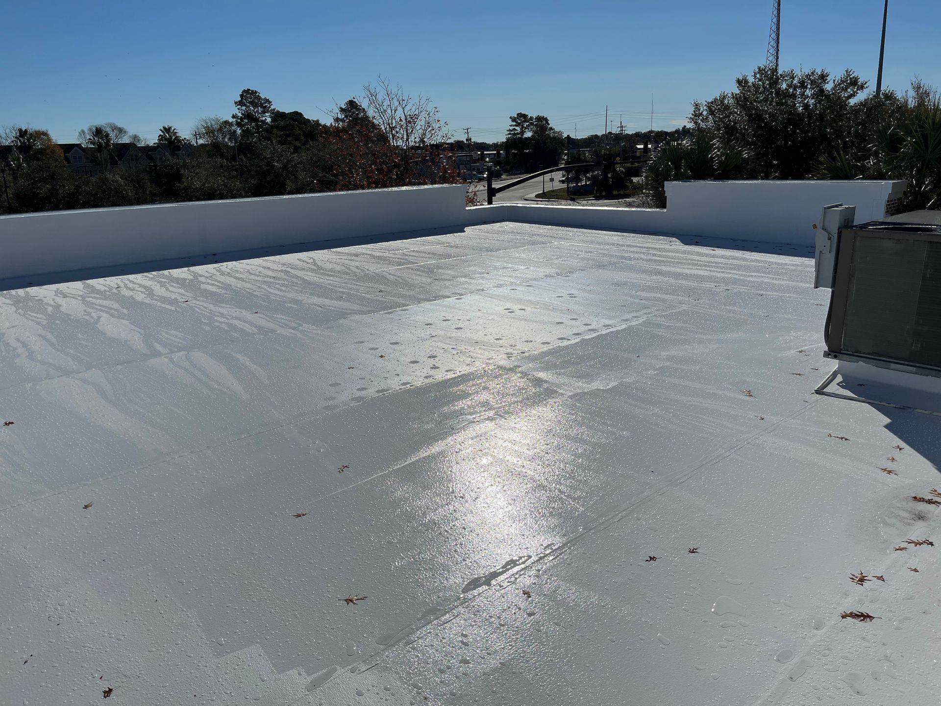White flat roof with wet coating, sunny day.