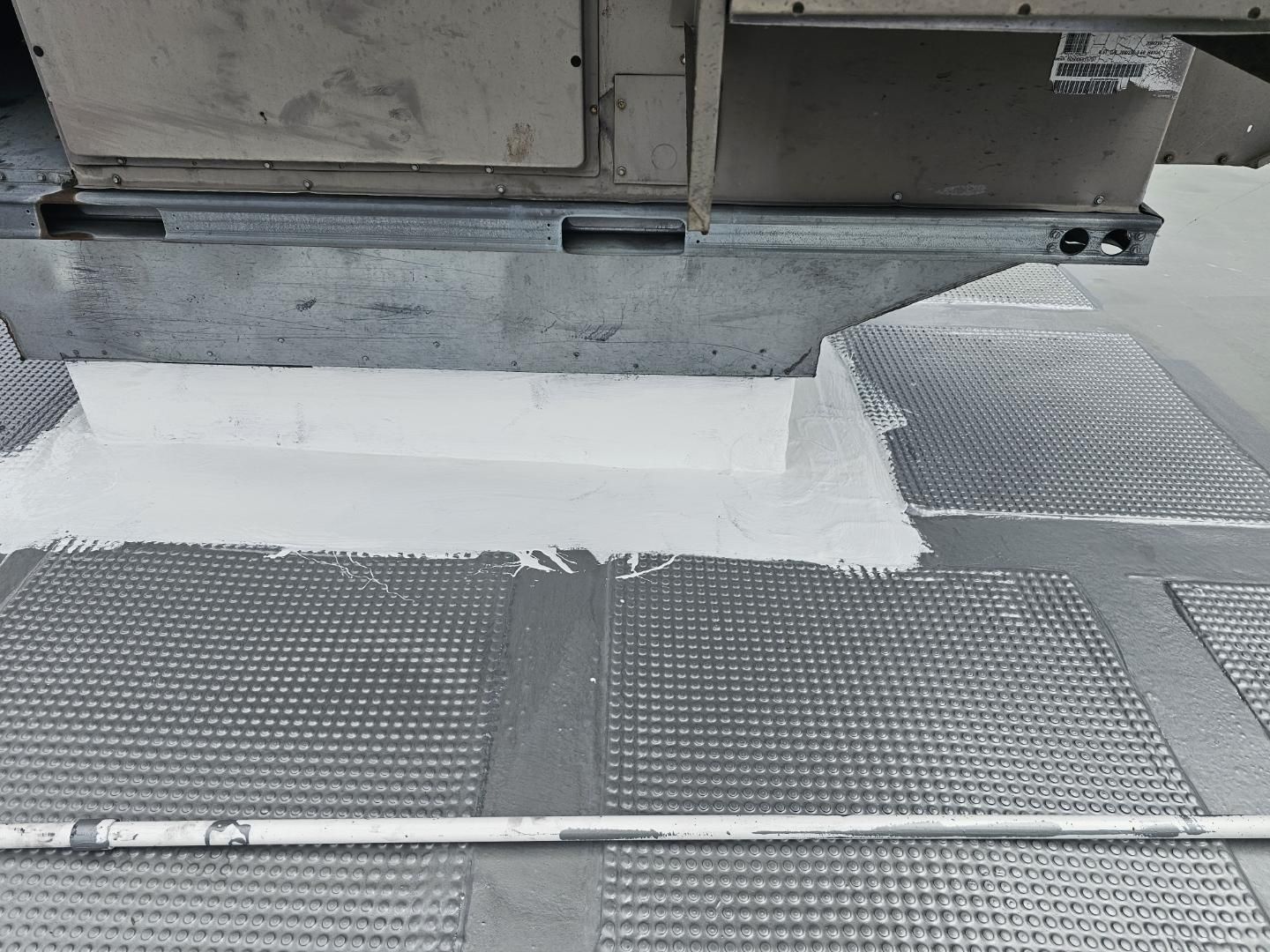 White fabric covering a section of a gray metal surface, likely for repair or insulation under a larger metal structure.