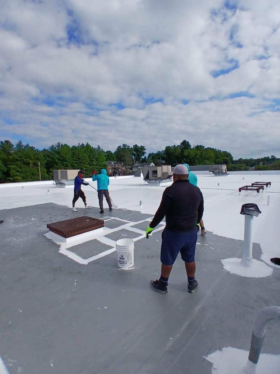 People painting a commercial roof, sunny day.
