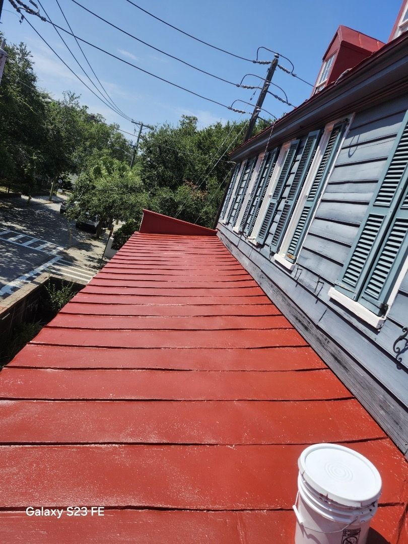 Red roof with blue shutters on a building. A white bucket sits at the bottom right.