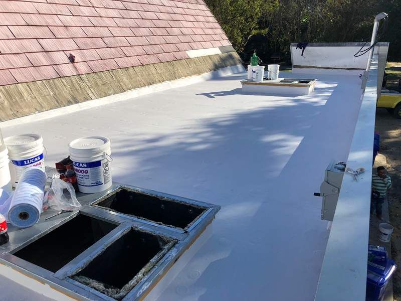 Flat white roof with skylights being worked on with tools and materials.