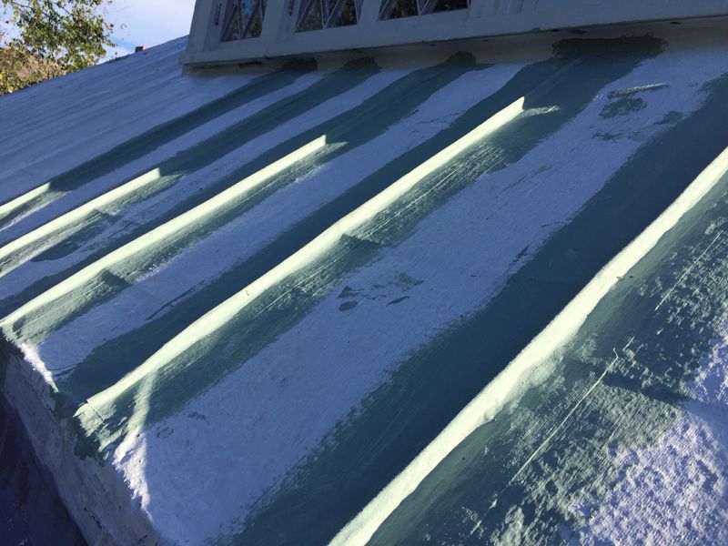 Close-up of a light blue metal roof with raised ribs. The sky is visible and a white frame is on the roof.