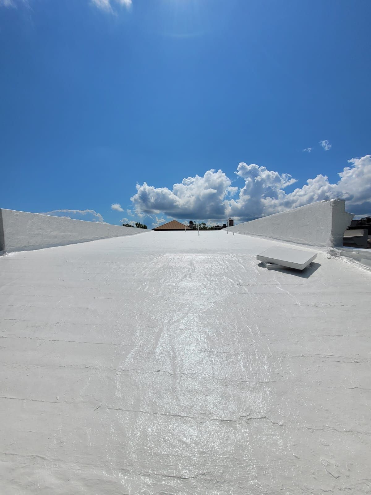 White rooftop with light streaks on it, blue sky with clouds in the background.