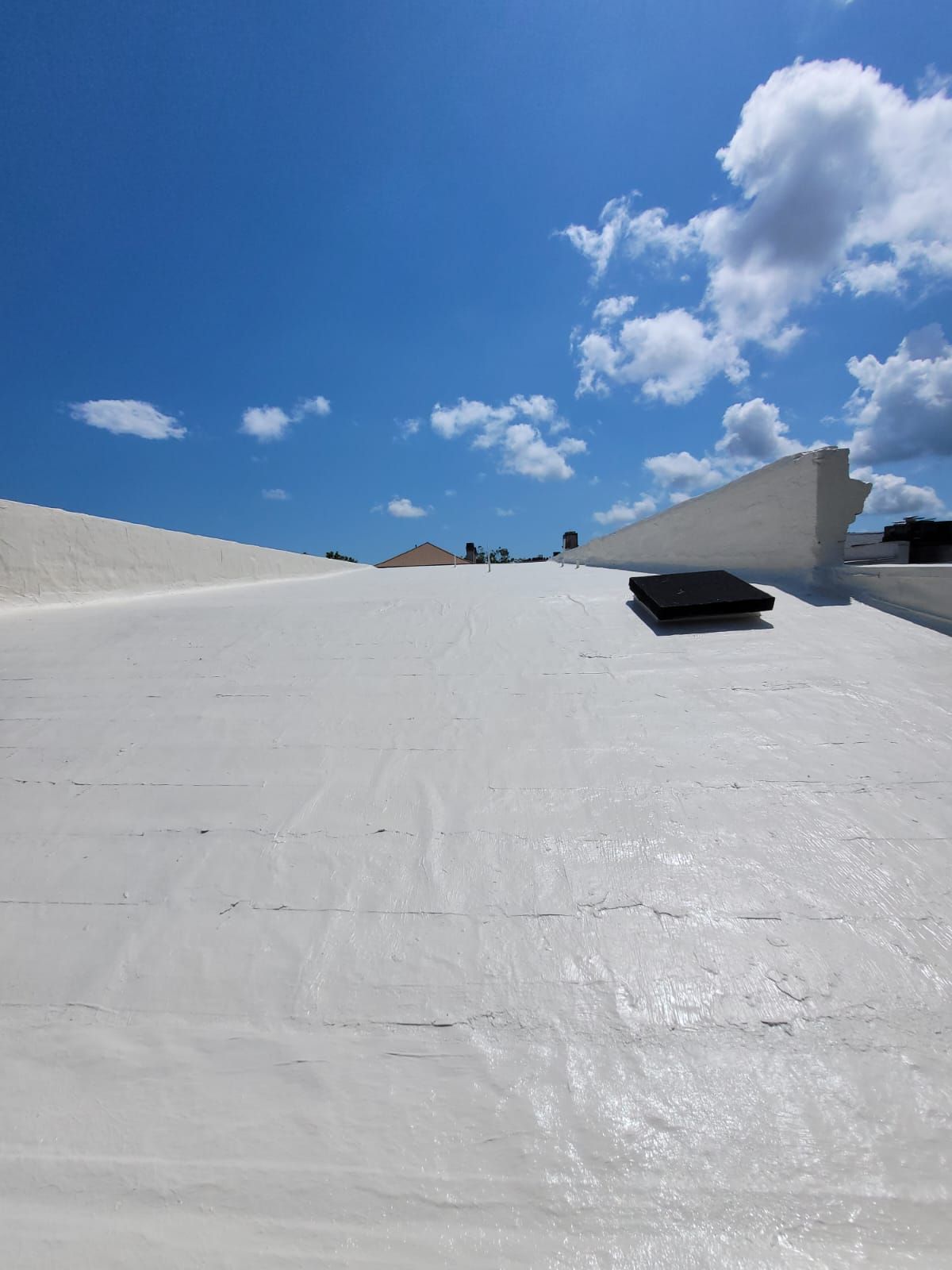 White roof under a bright blue sky with scattered clouds.