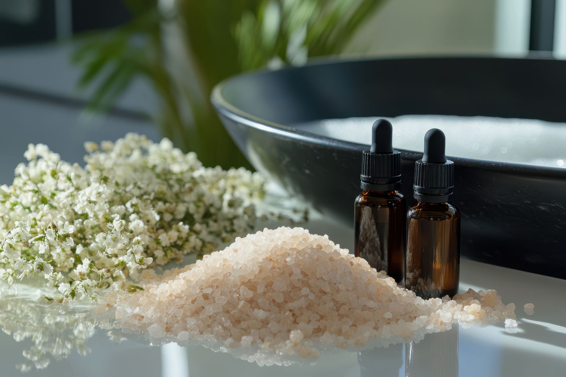 Una bottiglia di olio essenziale è posta accanto a un mucchio di sale marino