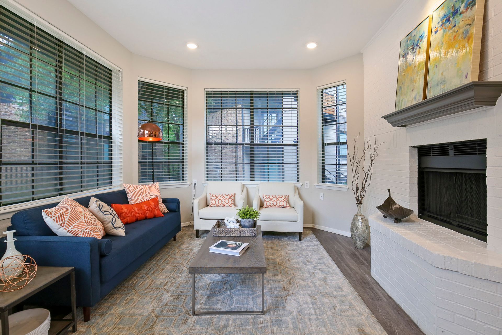 Living room with blue couch, white chairs, fireplace, and large windows.
