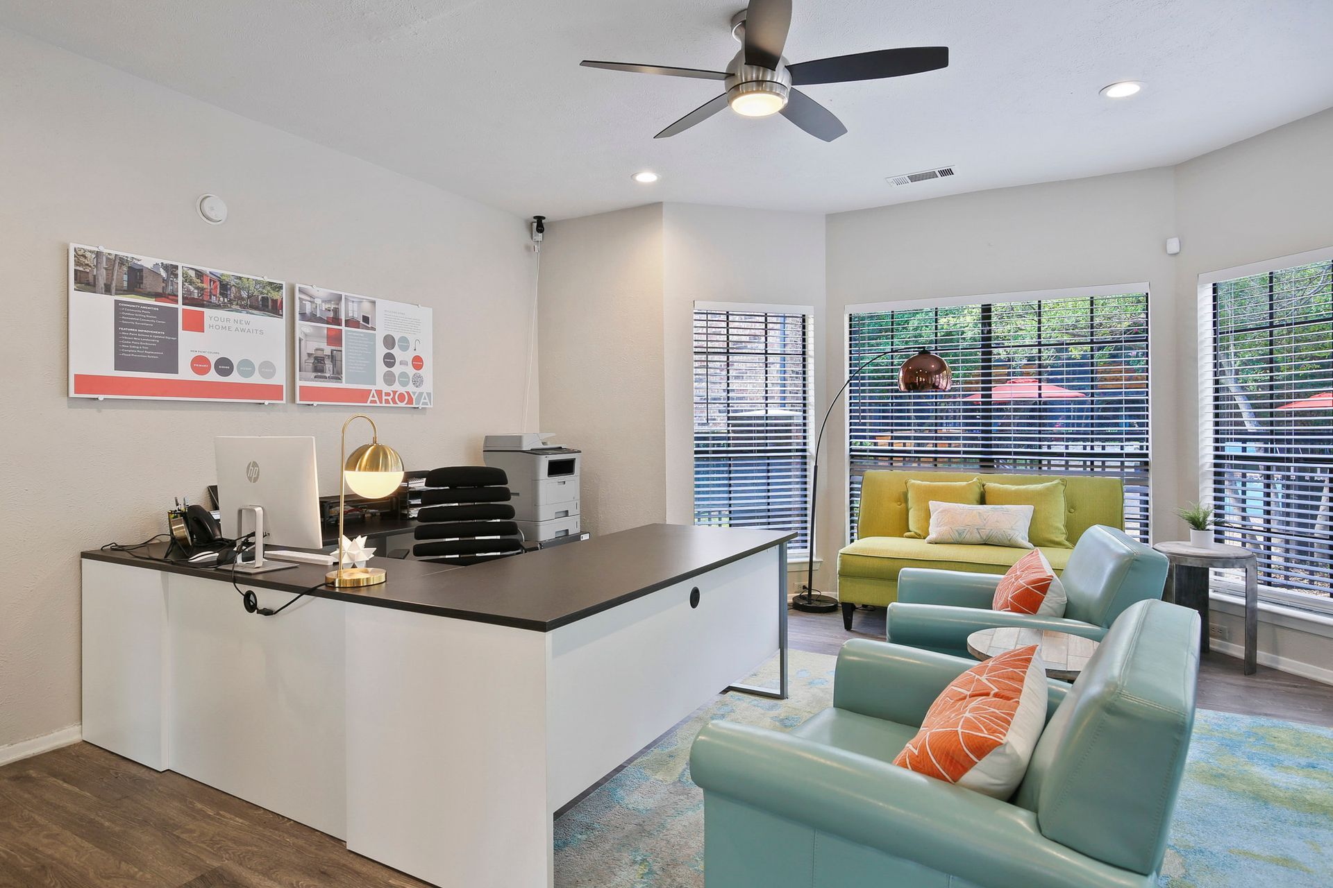Reception area with a desk, chairs, and a couch near a window.
