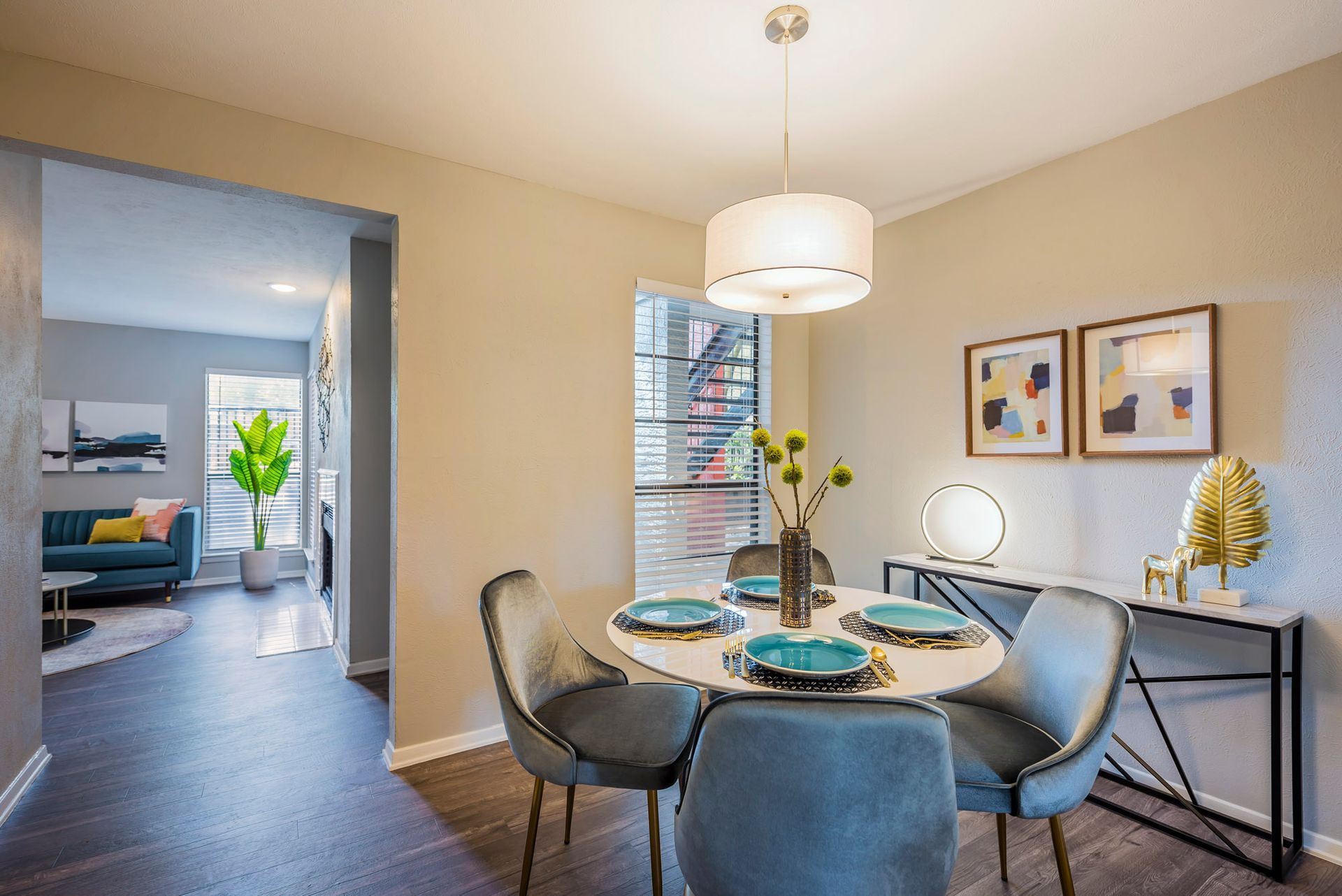 Dining area with round table, four blue chairs, and a console table.