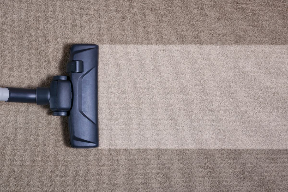A vacuum cleaner is cleaning a carpet with a brush.