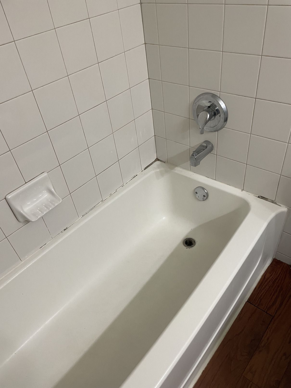 A white bathtub in a bathroom with white tiles