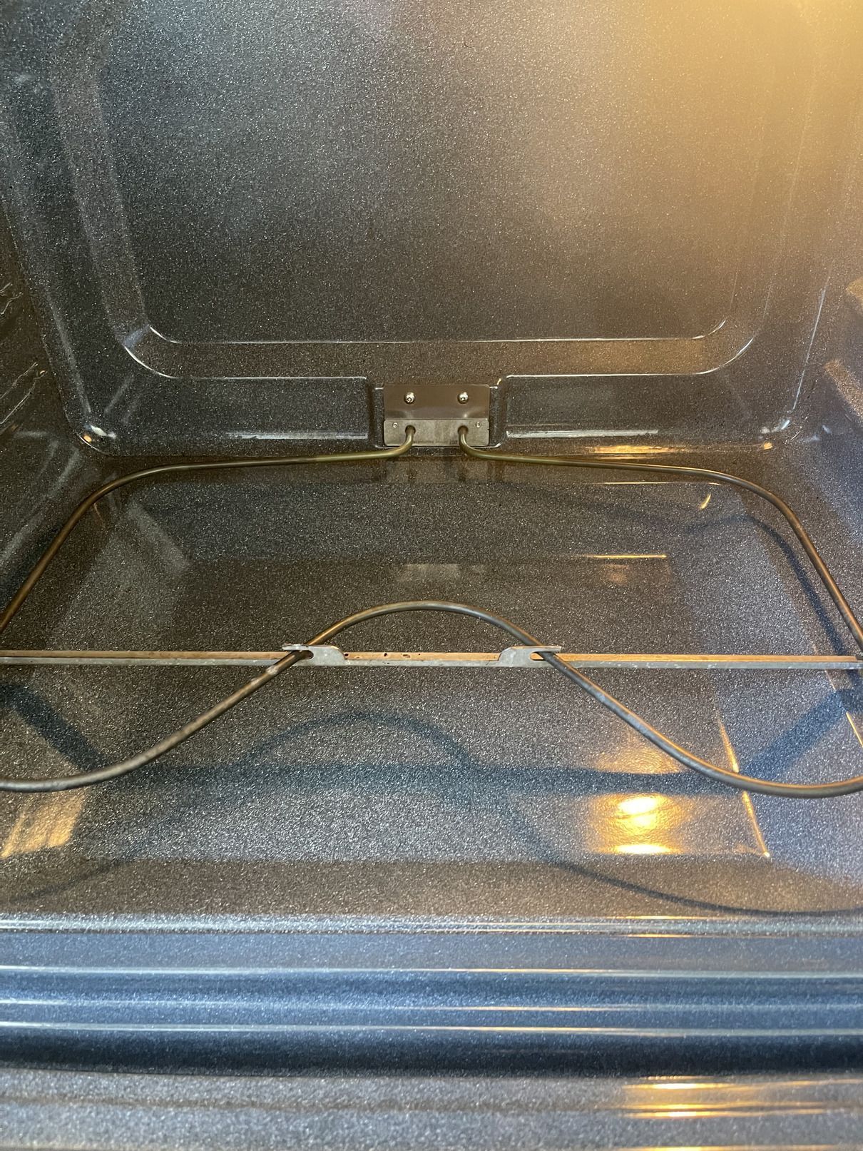 The inside of an oven with a wire hanging out of it.