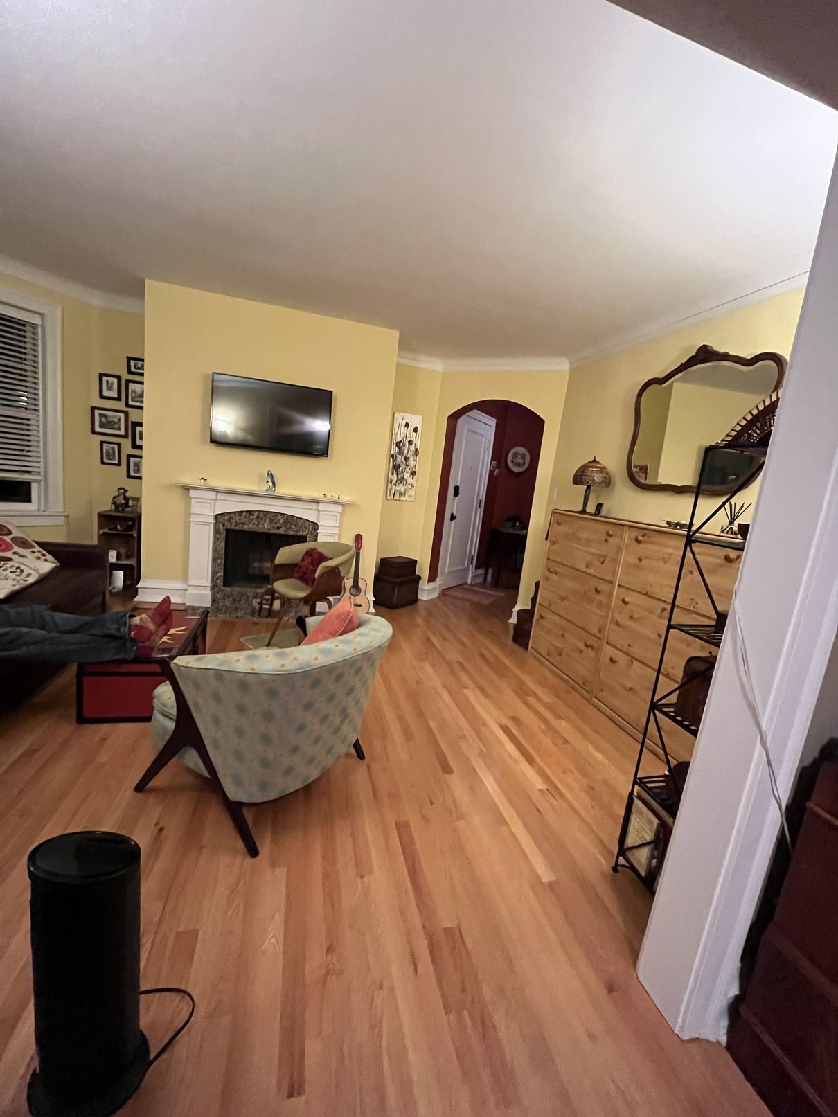 A living room with hardwood floors , a fireplace and a flat screen tv.