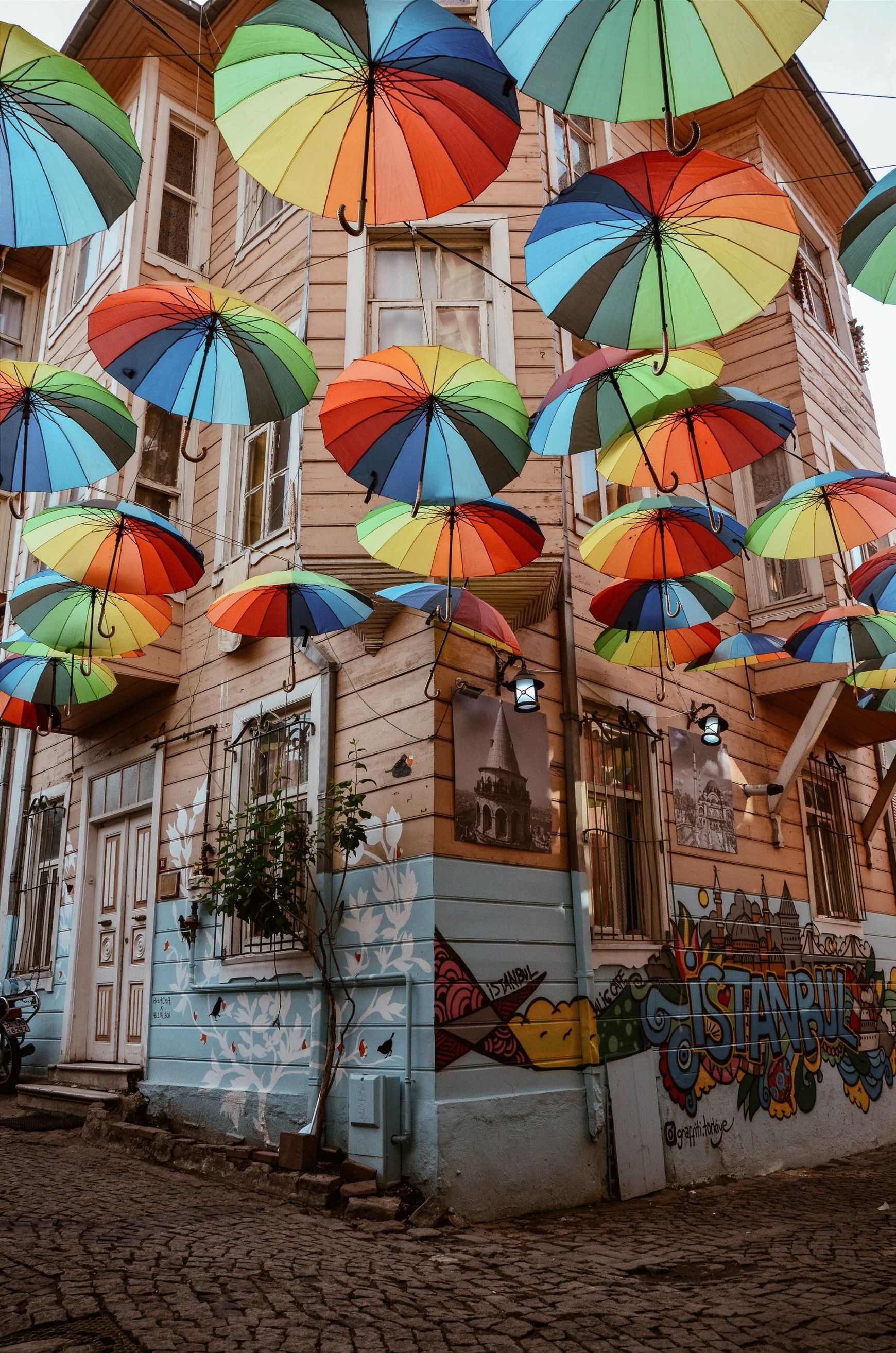 a bunch of colorful umbrellas are hanging up in the street.