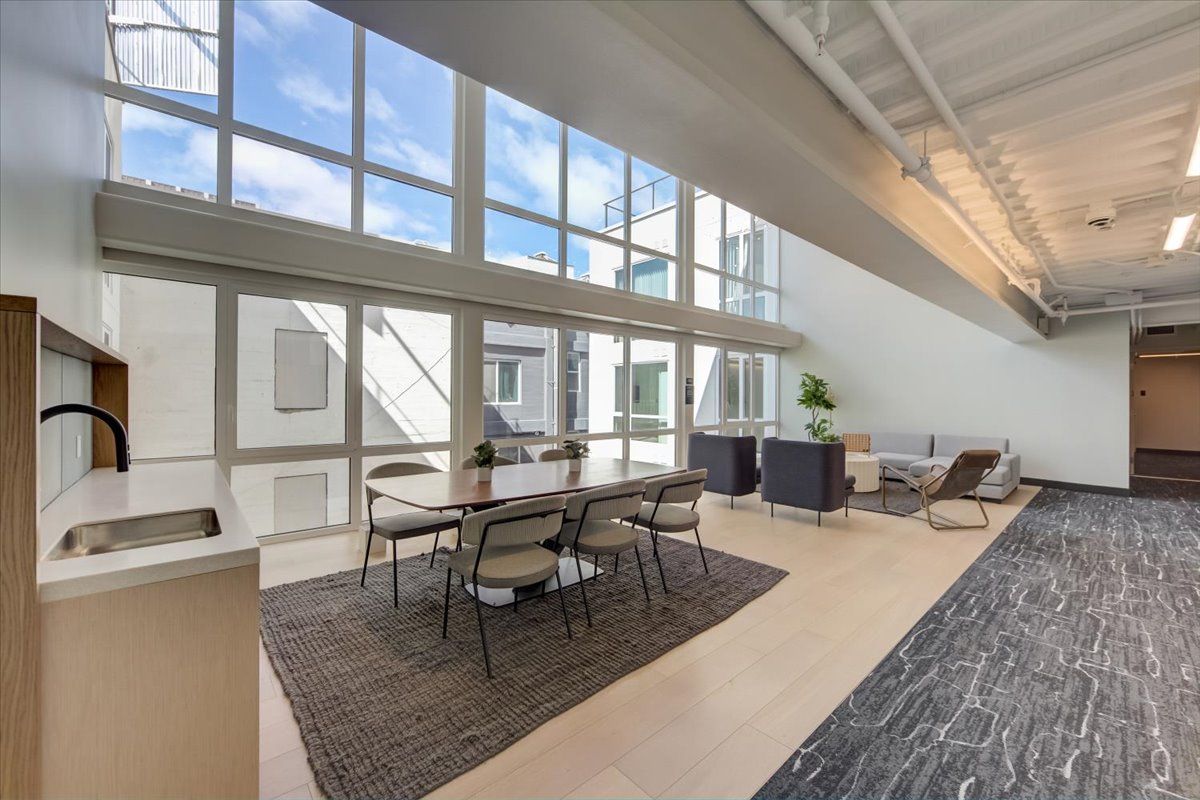 Spacious room with large windows, dining table, and seating area. Natural light floods the space.