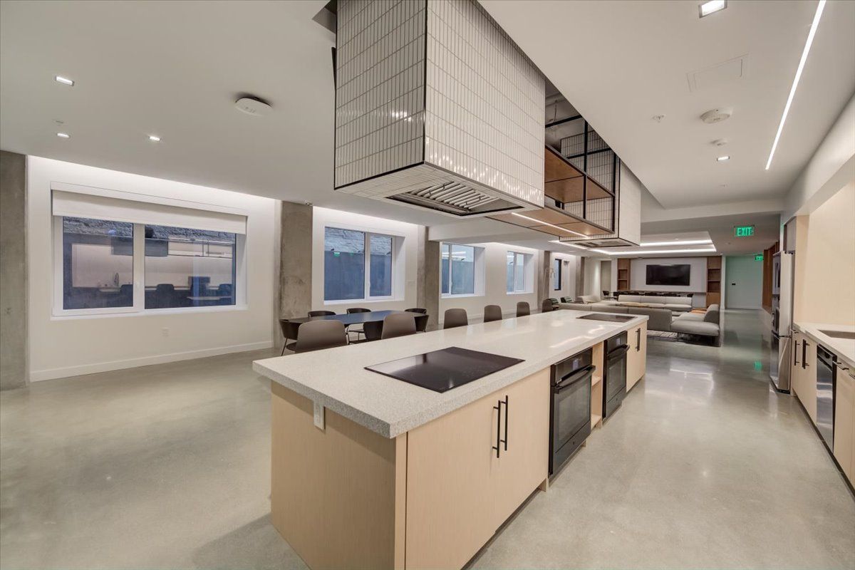 Modern kitchen with island, range hood, and seating area. Bright, spacious with neutral tones and large windows.