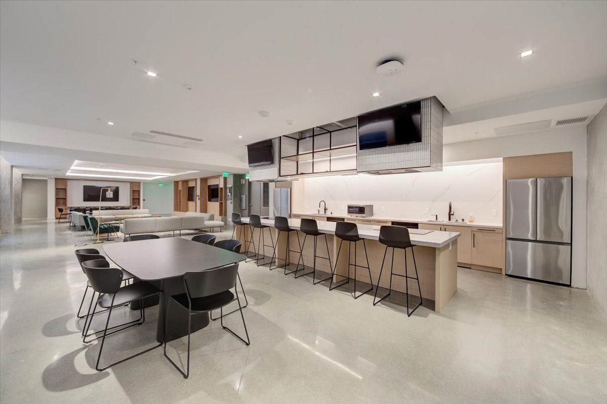 Modern communal kitchen with a dining area, bar seating, and stainless steel appliances.
