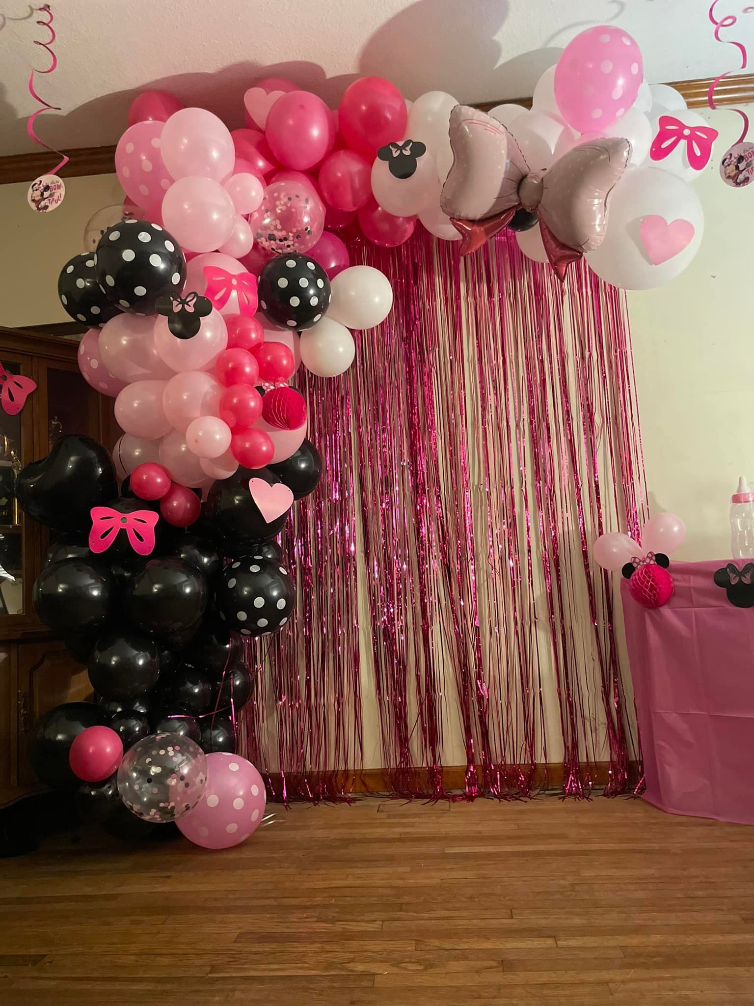 A room decorated with pink and black balloons and tinsel.